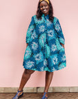 The model is wearing turquoise, black, pacific blue, slate and white feathered spiral print dress