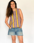 The model is wearing olive-yellow, blue, orange and white geometric printed tank