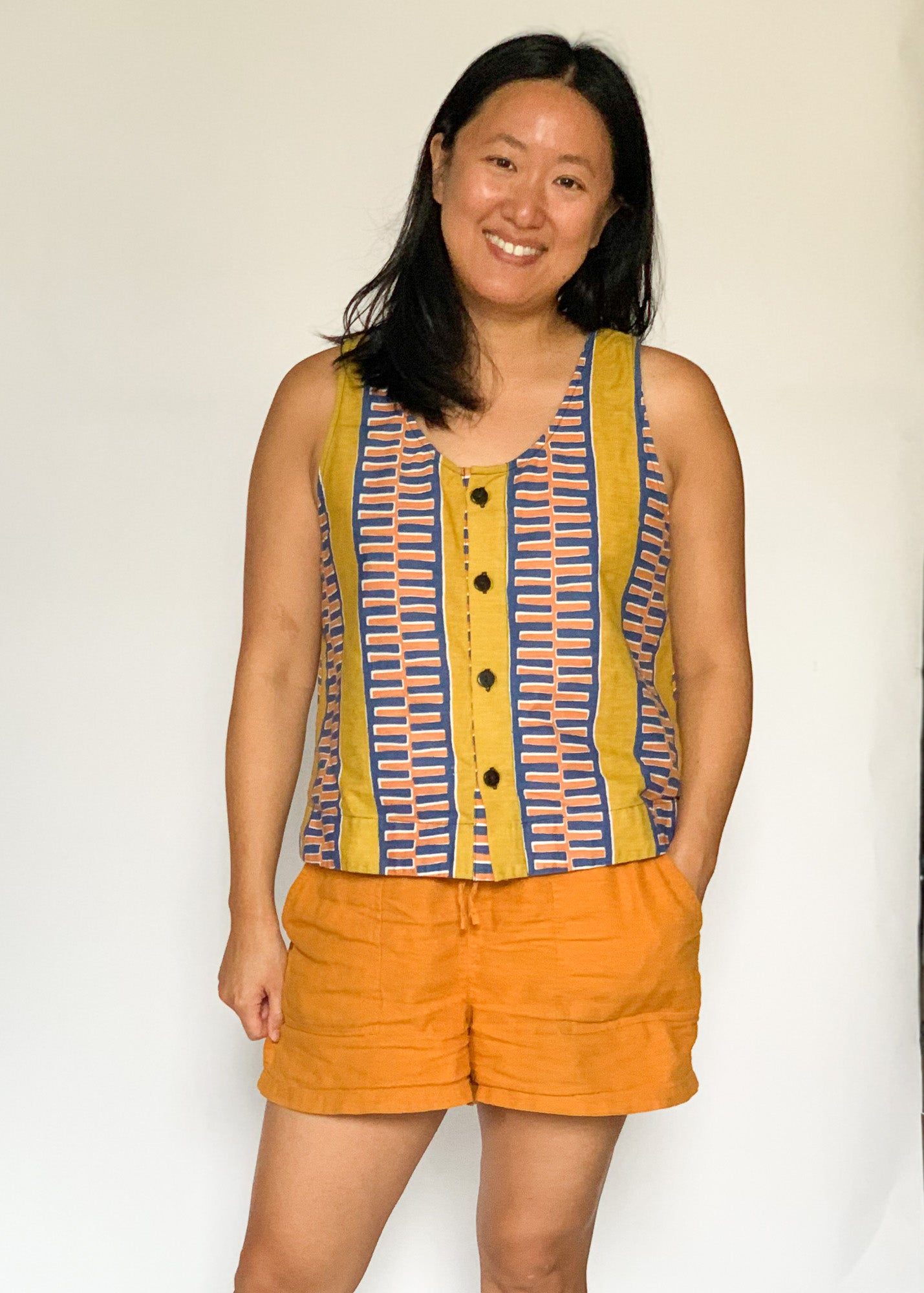 The model is wearing olive-yellow, blue, orange and white geometric printed tank