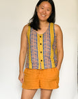 The model is wearing olive-yellow, blue, orange and white geometric printed tank