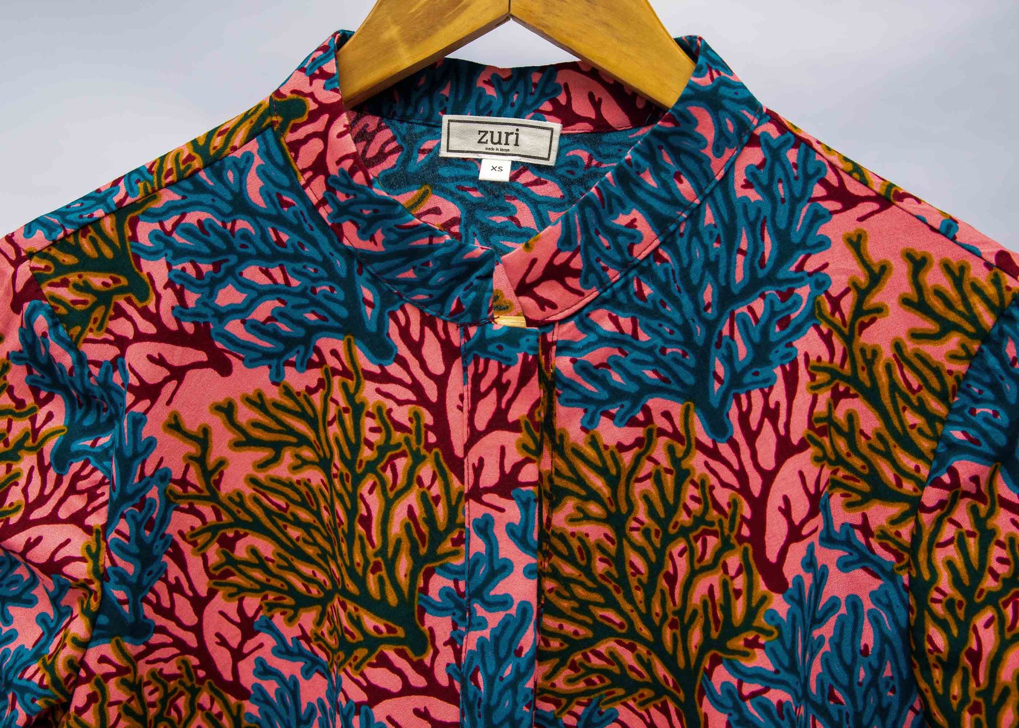 Display of a  blue, yellow and pink coral print shirt dress 