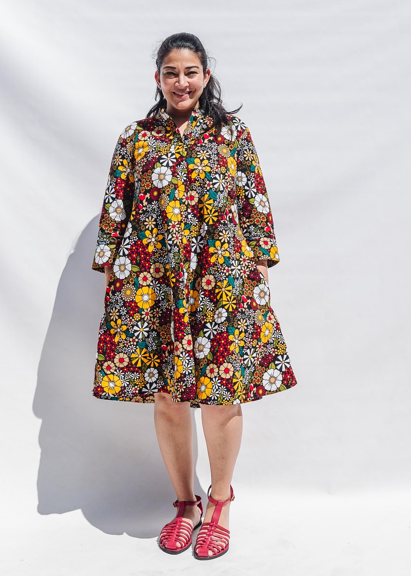 The model is wearing colorful flower print dress