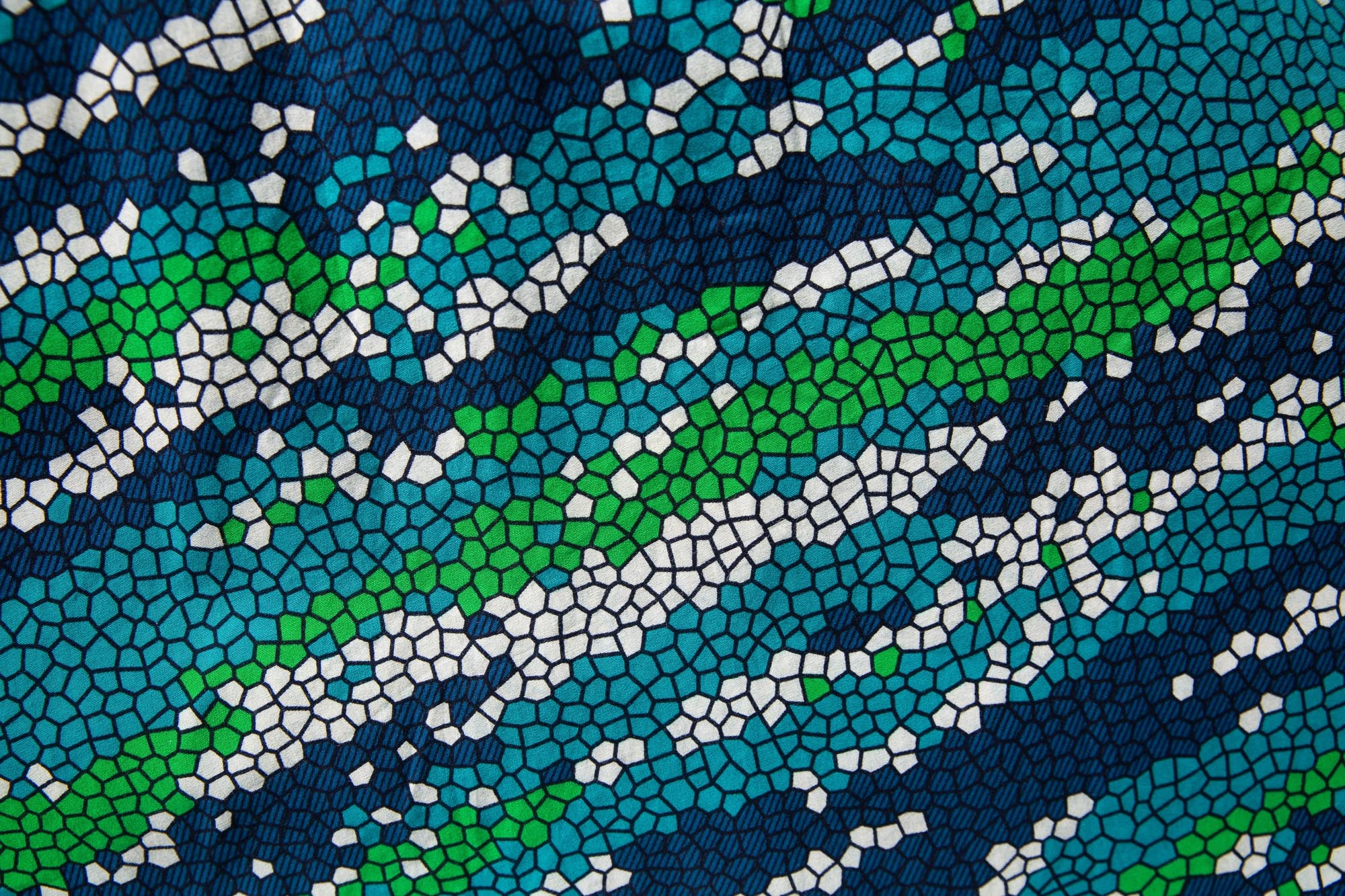 Close up display of black, green, white, blue and aqua print dress