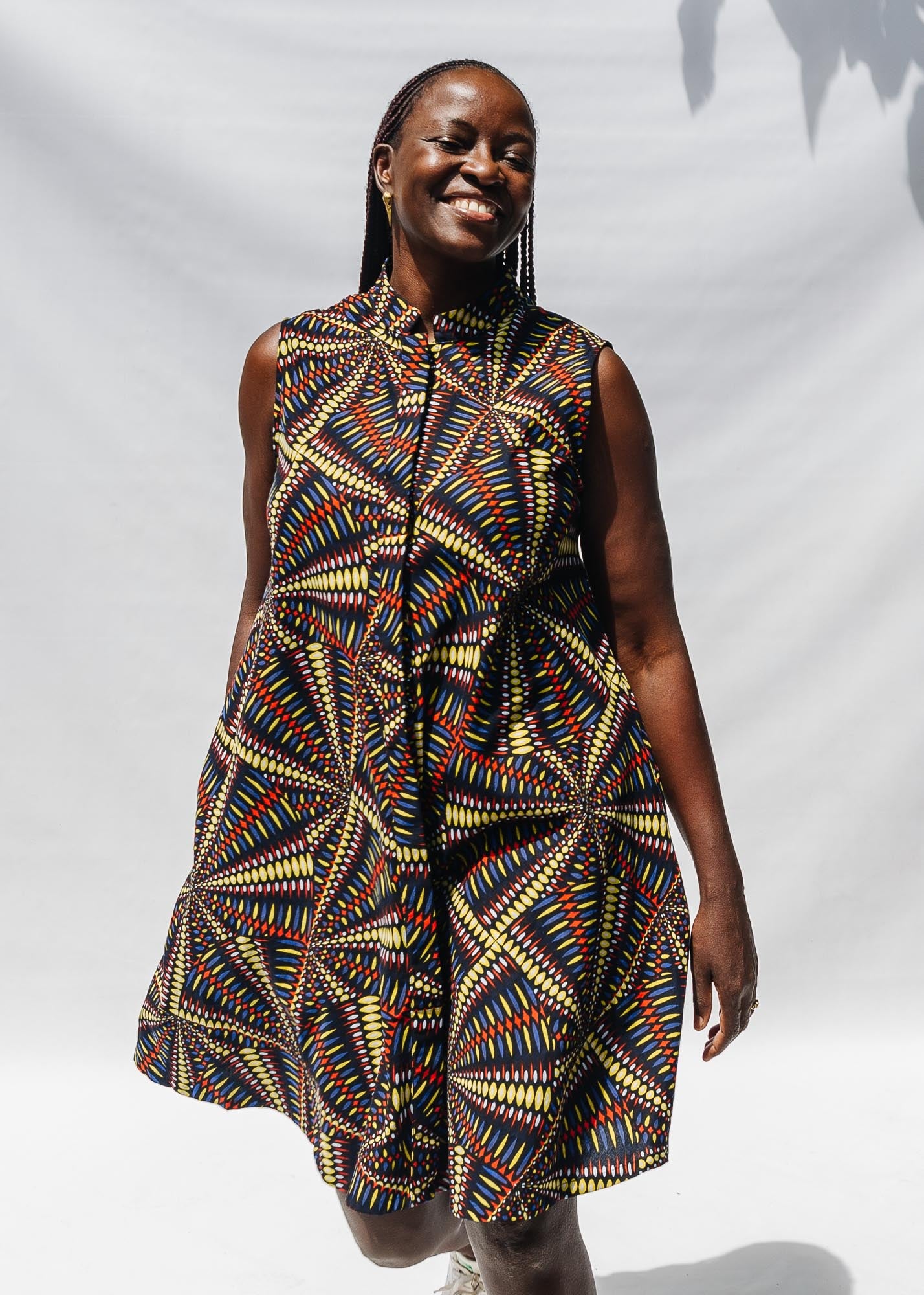 The model is wearing multi-colored abstract print dress