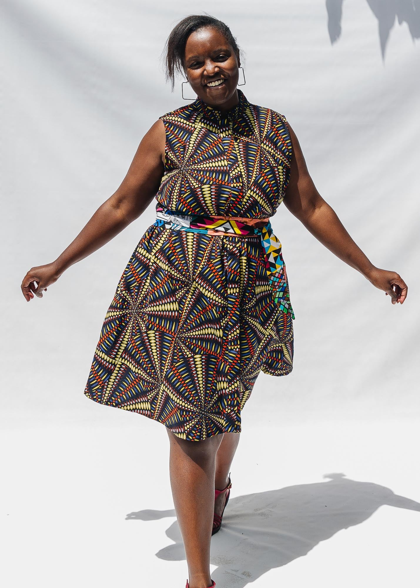 The model is wearing multi-colored abstract print dress