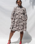 The model is wearing black, off white, gray and dark gray abstract print dress