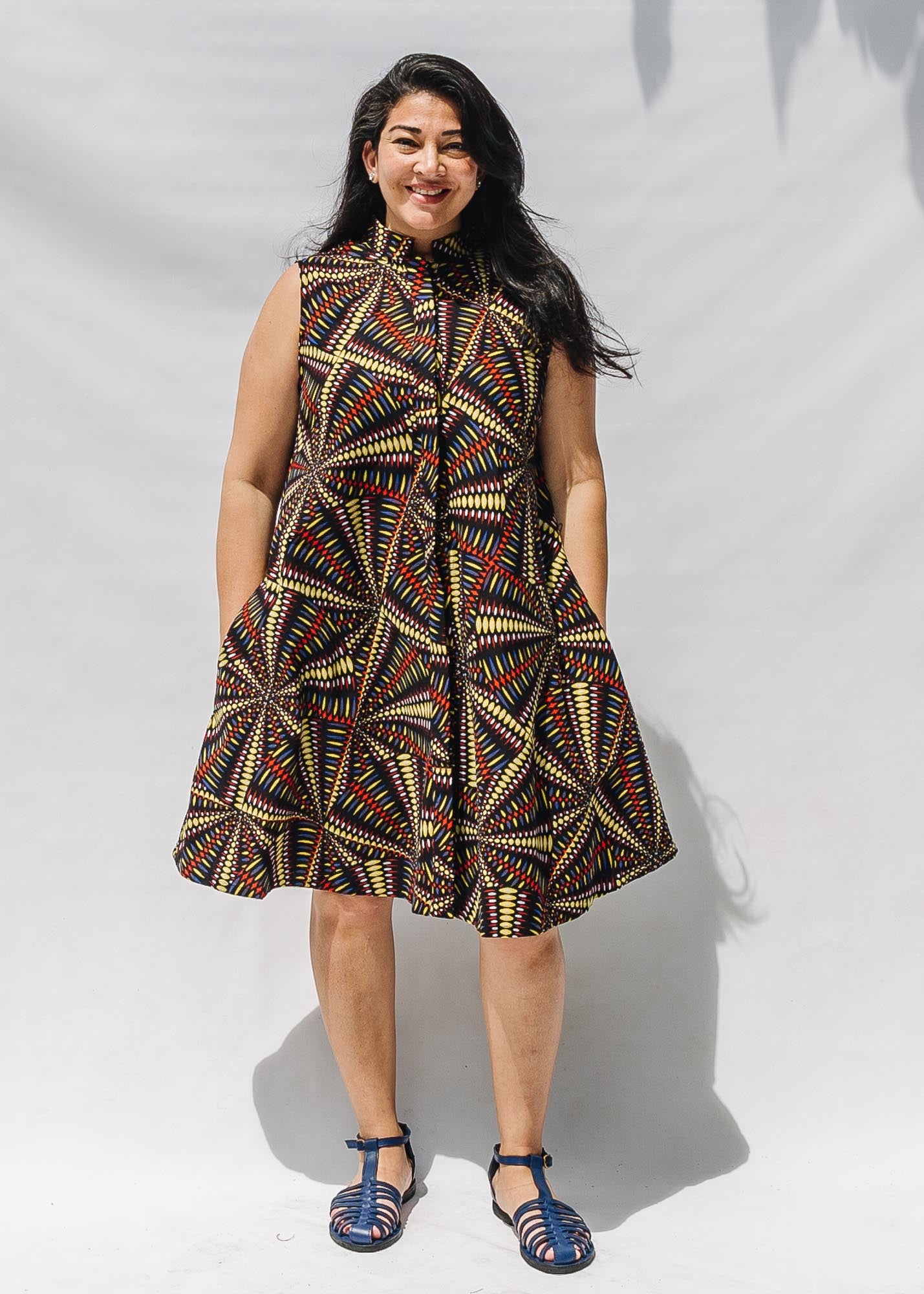 The model is wearing multi-colored abstract print dress