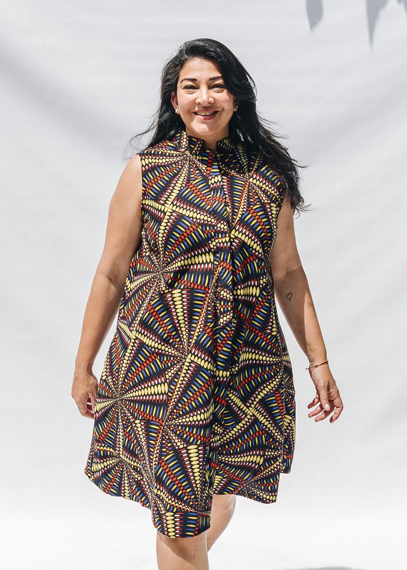 The model is wearing multi-colored abstract print dress