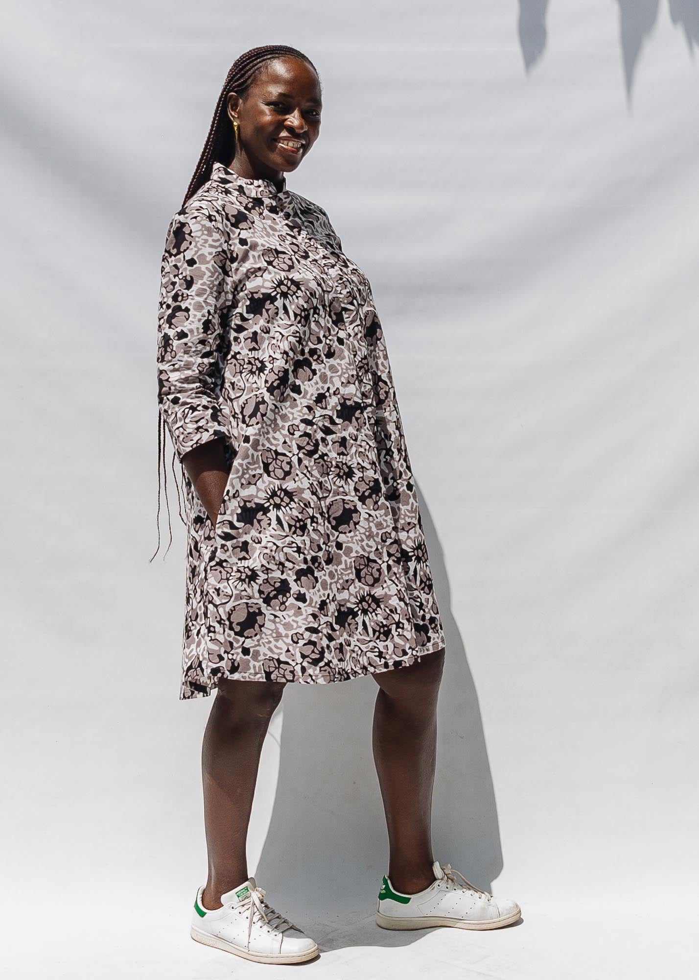 The model is wearing black, off white, gray and dark gray abstract print dress