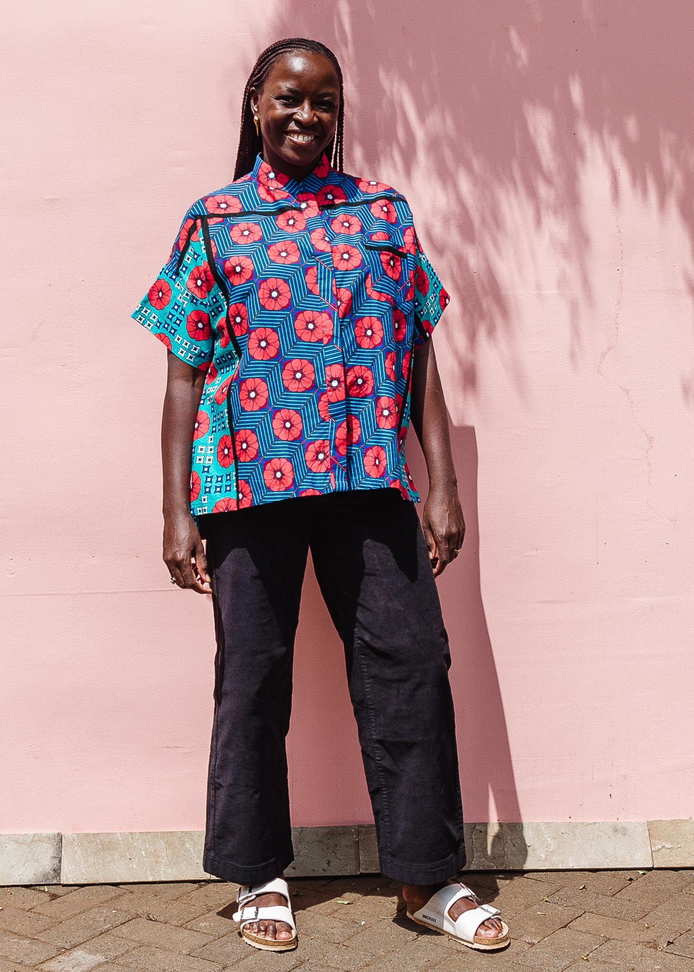 The model is wearing blue, pink, turquoise, black and white mixed pattern floral print shirt