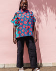 The model is wearing blue, pink, turquoise, black and white mixed pattern floral print shirt