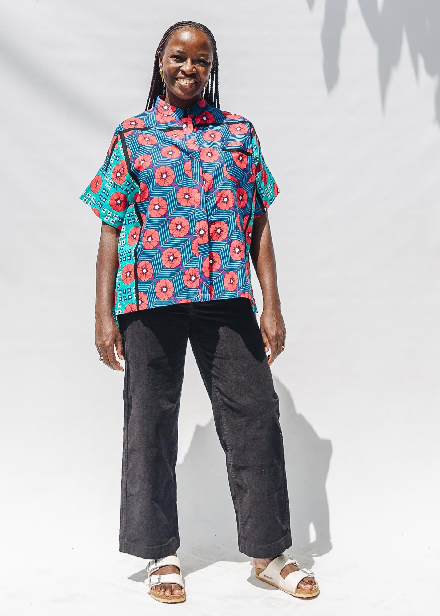 The model is wearing blue, pink, turquoise, black and white mixed pattern floral print shirt