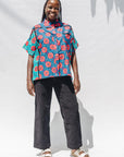 The model is wearing blue, pink, turquoise, black and white mixed pattern floral print shirt