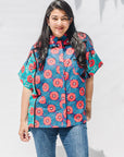 The model is wearing blue, pink, turquoise, black and white mixed pattern floral print shirt