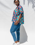 The model is wearing blue, pink, turquoise, black and white mixed pattern floral print shirt