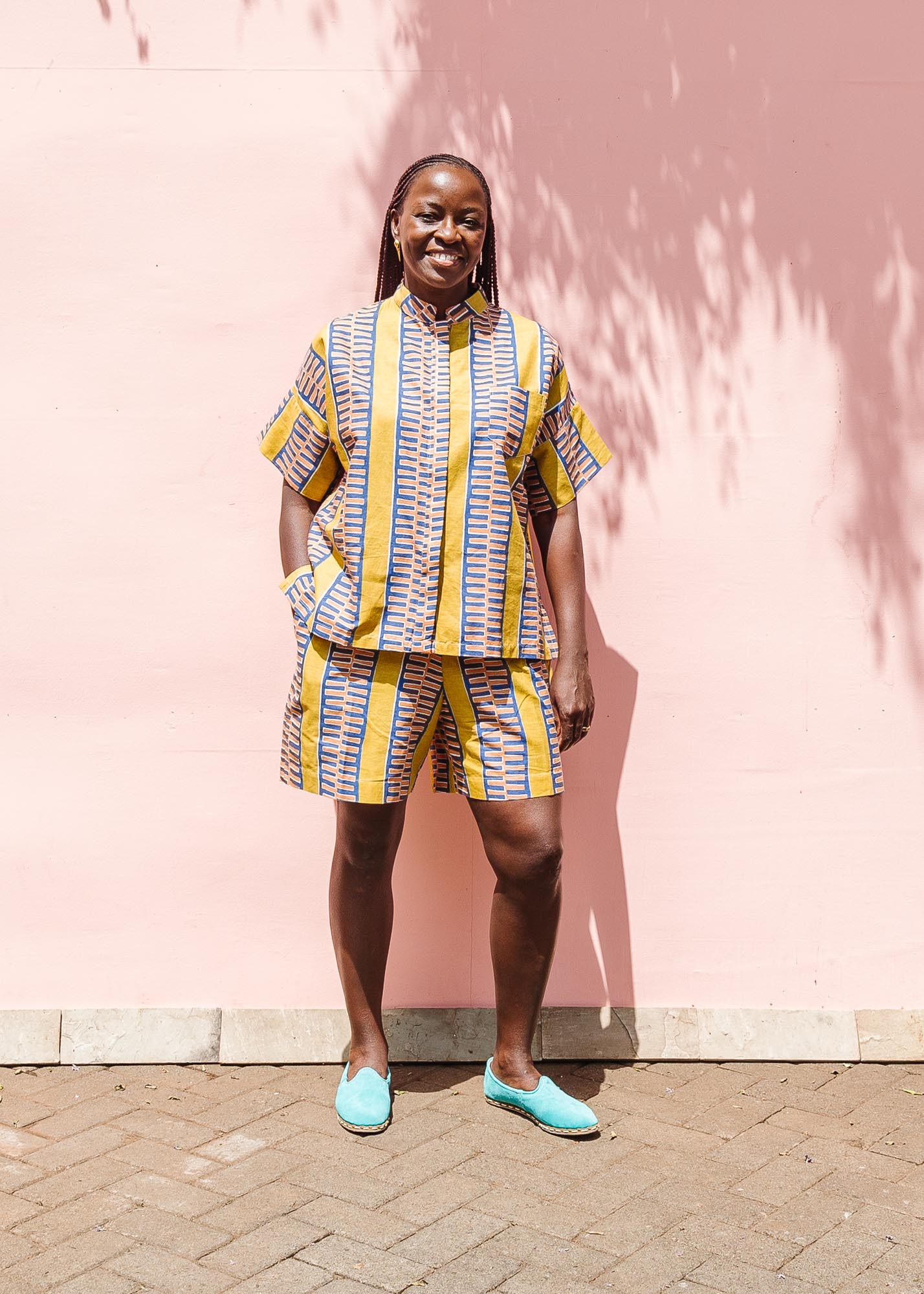 The model is wearing olive-yellow, blue, orange and white geometric printed shirt