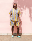 The model is wearing olive-yellow, blue, orange and white geometric printed shirt