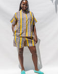 The model is wearing olive-yellow, blue, orange and white geometric printed shirt