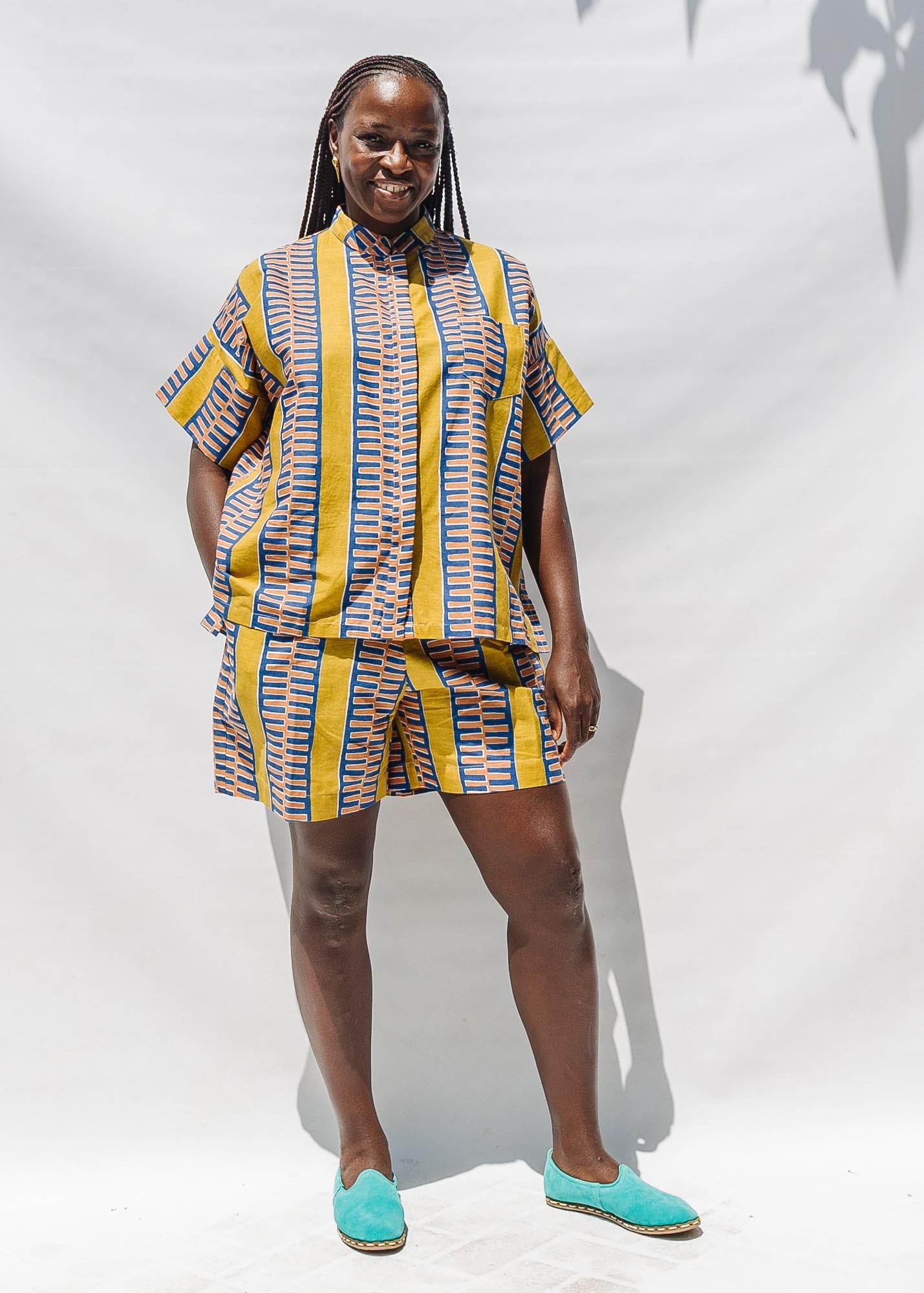 The model is wearing olive-yellow, blue, orange and white printed shorts