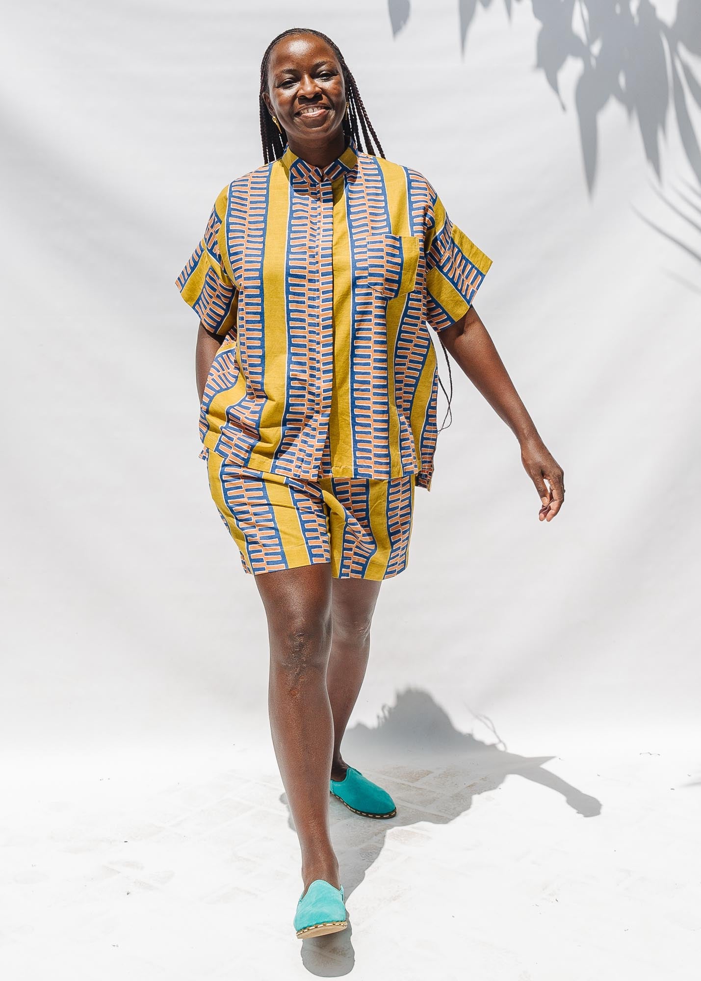 The model is wearing olive-yellow, blue, orange and white geometric printed shirt