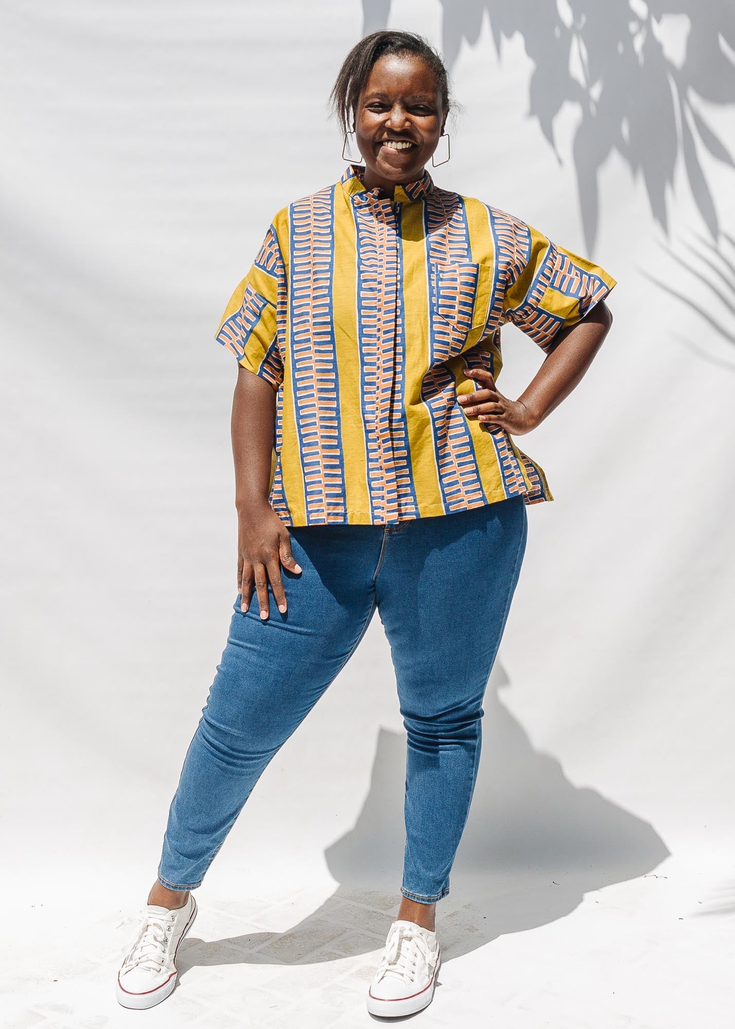 The model is wearing olive-yellow, blue, orange and white geometric printed shirt