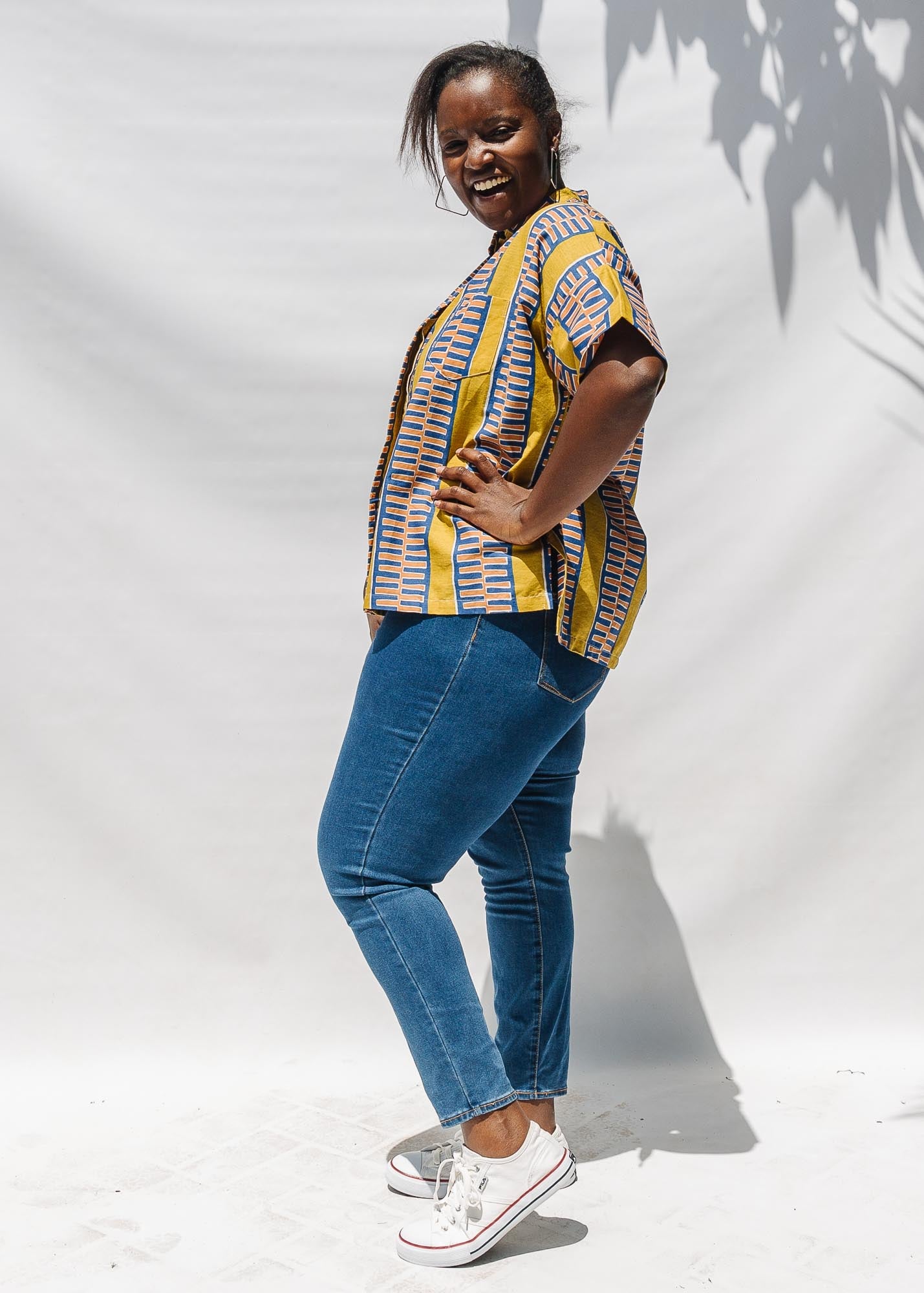 The model is wearing olive-yellow, blue, orange and white geometric printed shirt