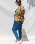 The model is wearing olive-yellow, blue, orange and white geometric printed shirt