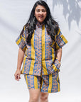 The model is wearing olive-yellow, blue, orange and white geometric printed shirt