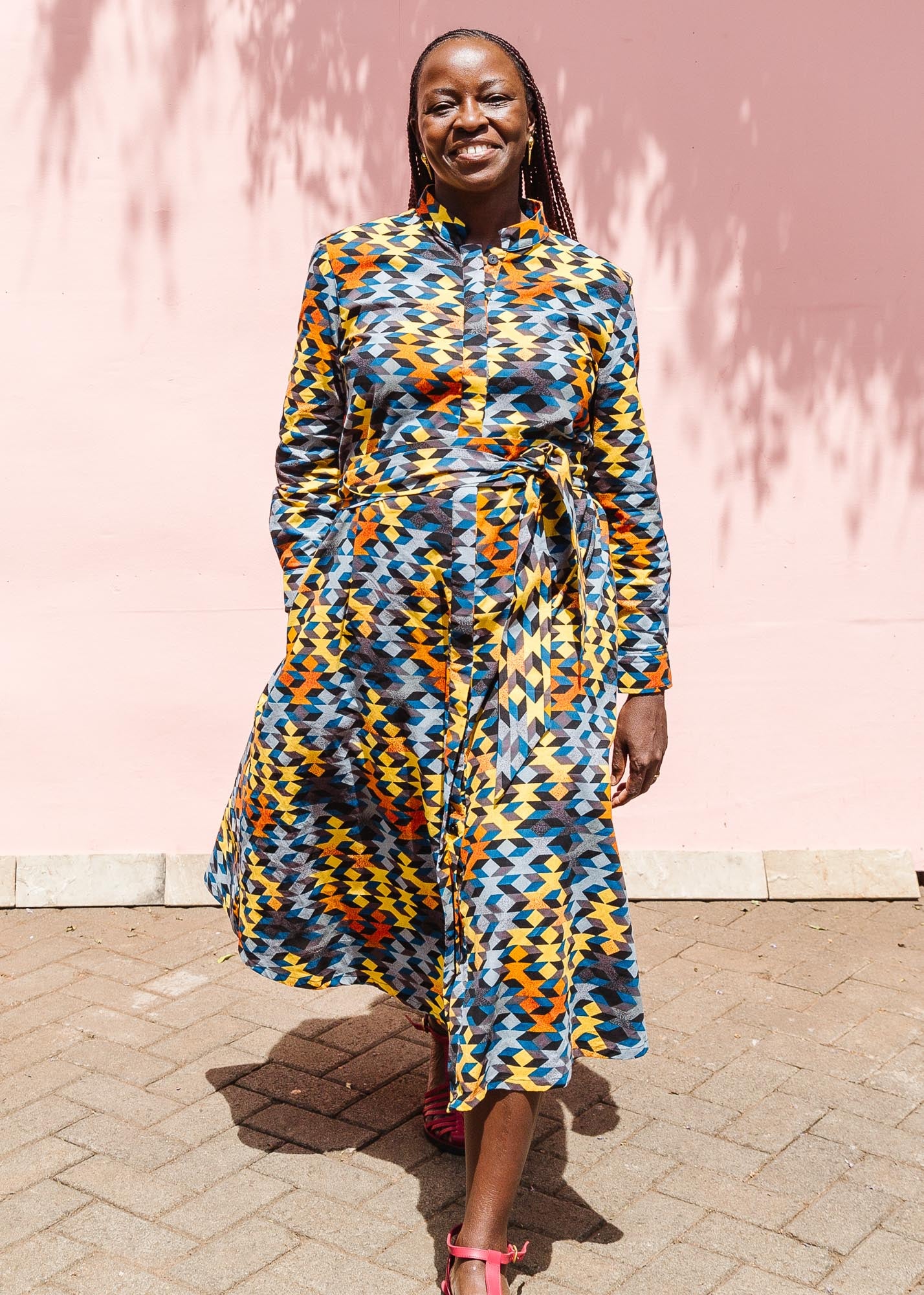 The model is wearing colorful geometric print dress