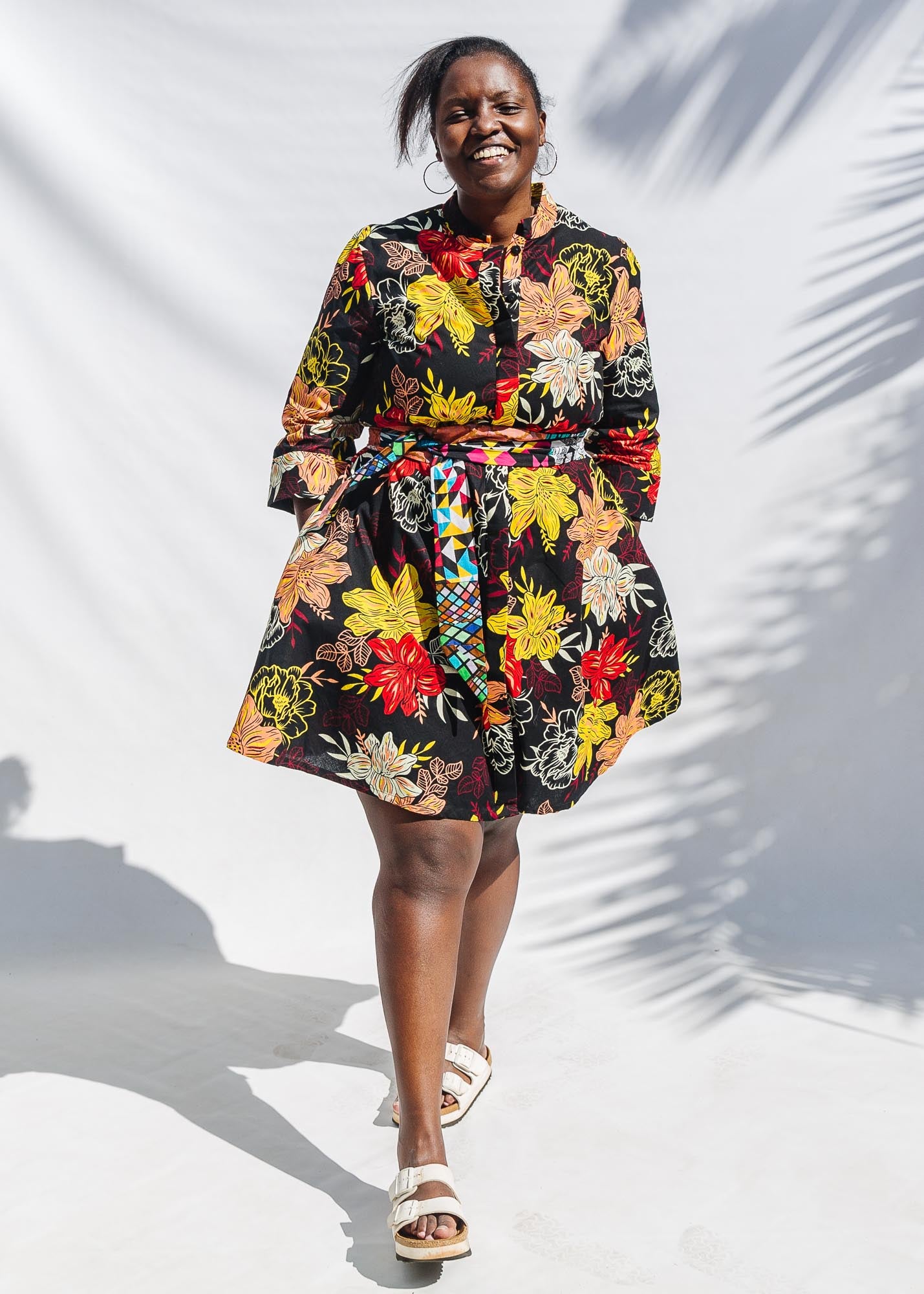 The model is wearing black, white, red, yellow, peach floral print dress