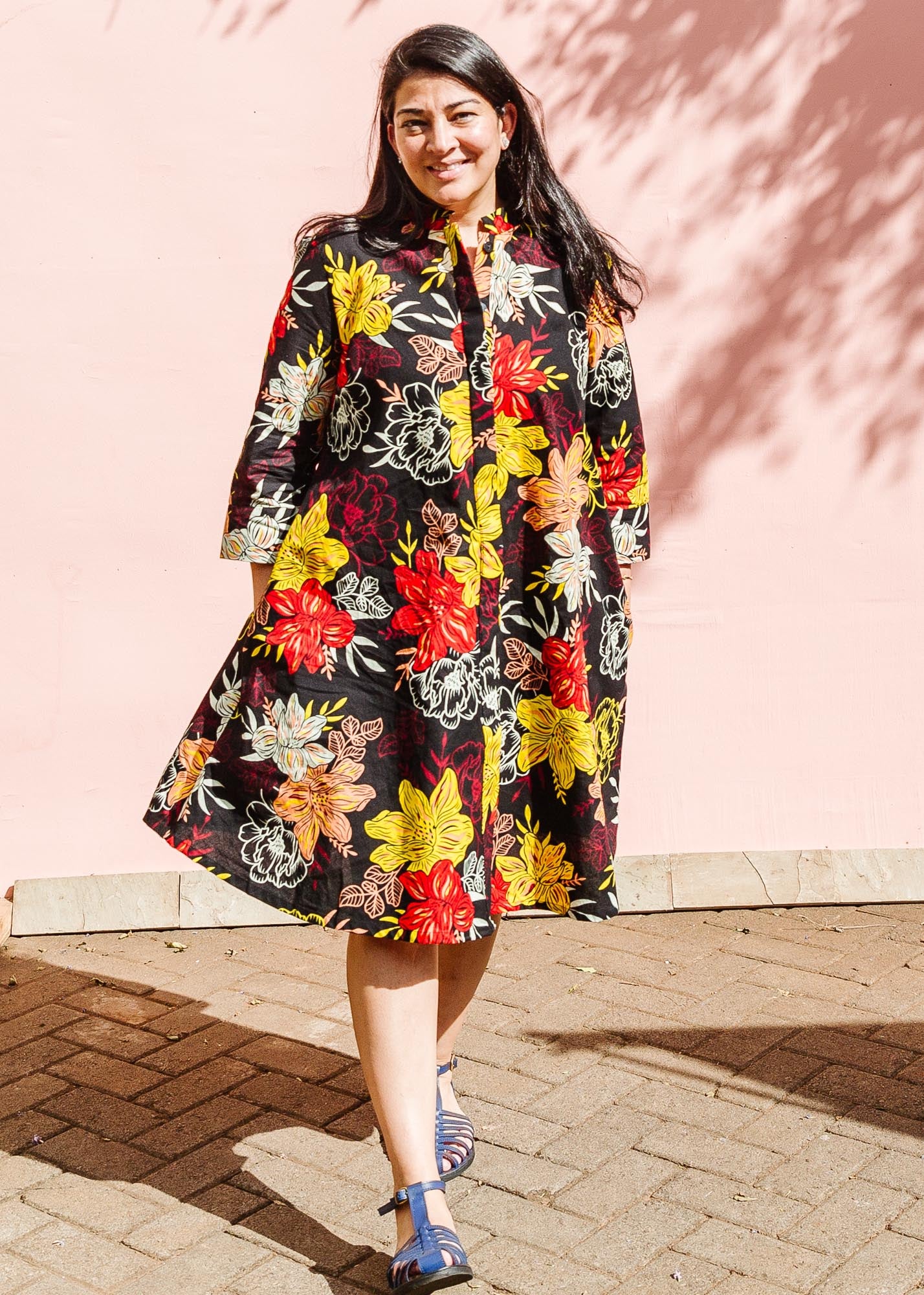 The model is wearing black, white, red, yellow, peach floral print dress