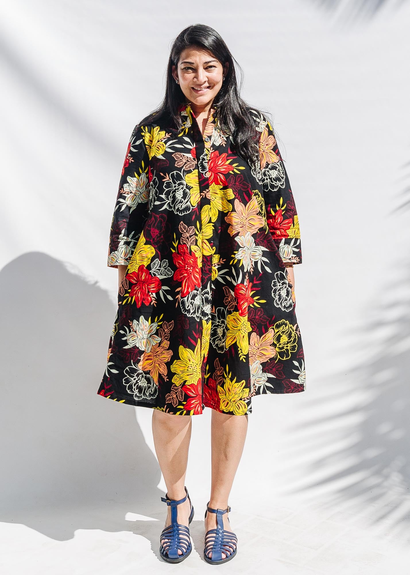 The model is wearing black, white, red, yellow, peach floral print dress