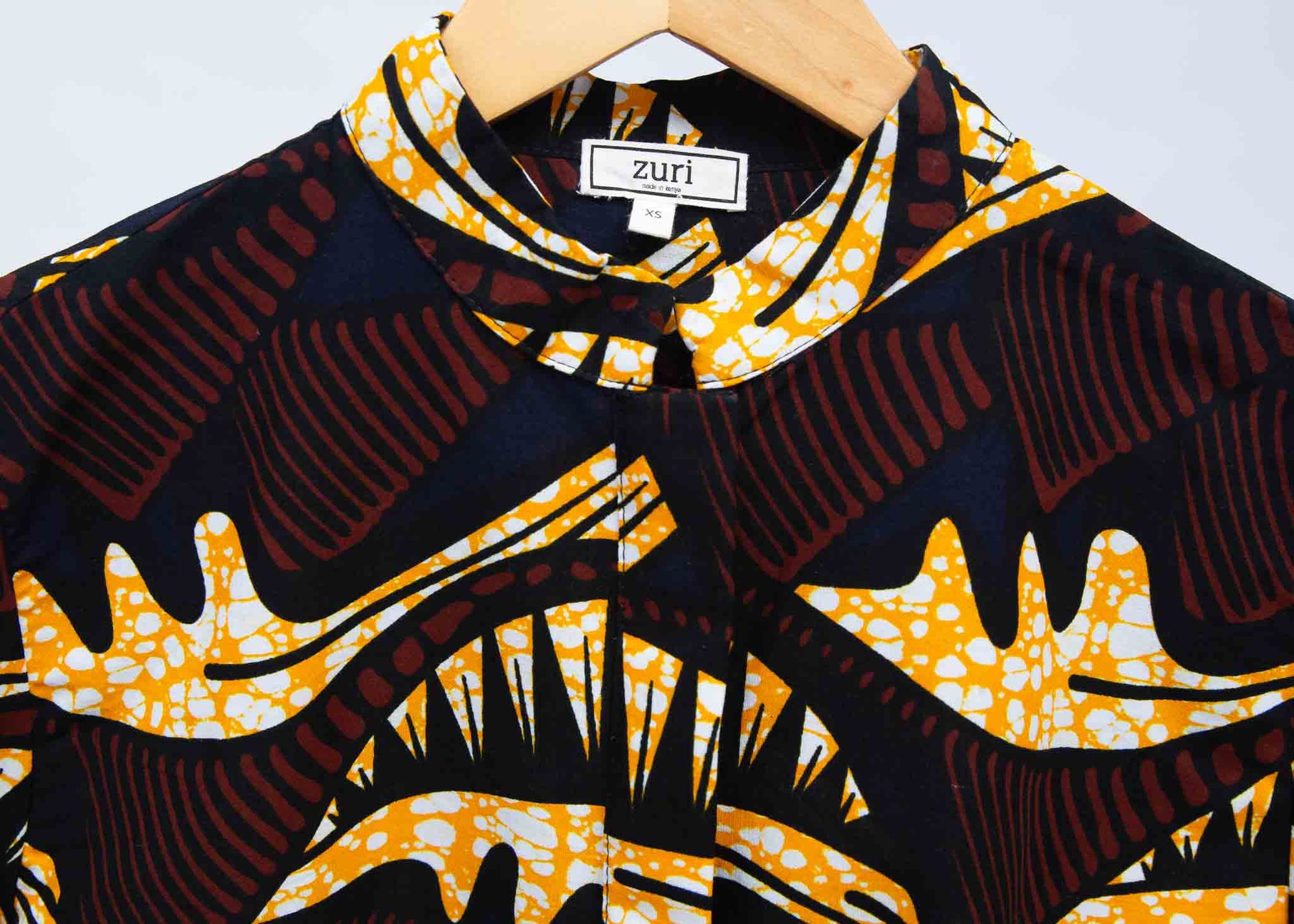 Display of long sleeve blouse with brown and yellow abstract print.