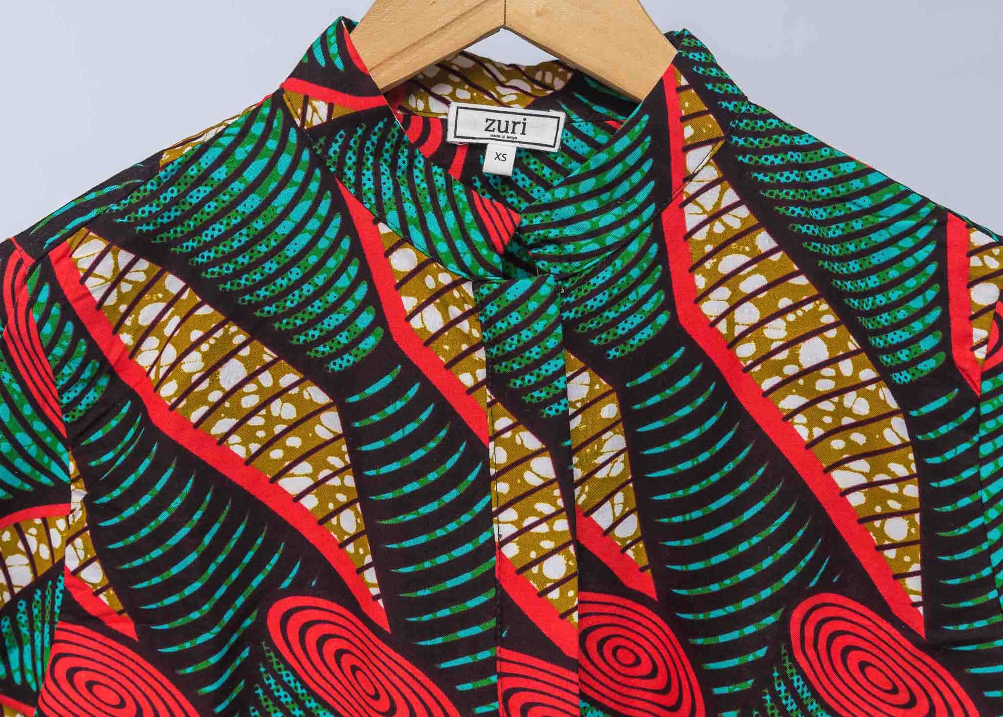 Display of green, red, black and brown scroll print long sleeve blouse.