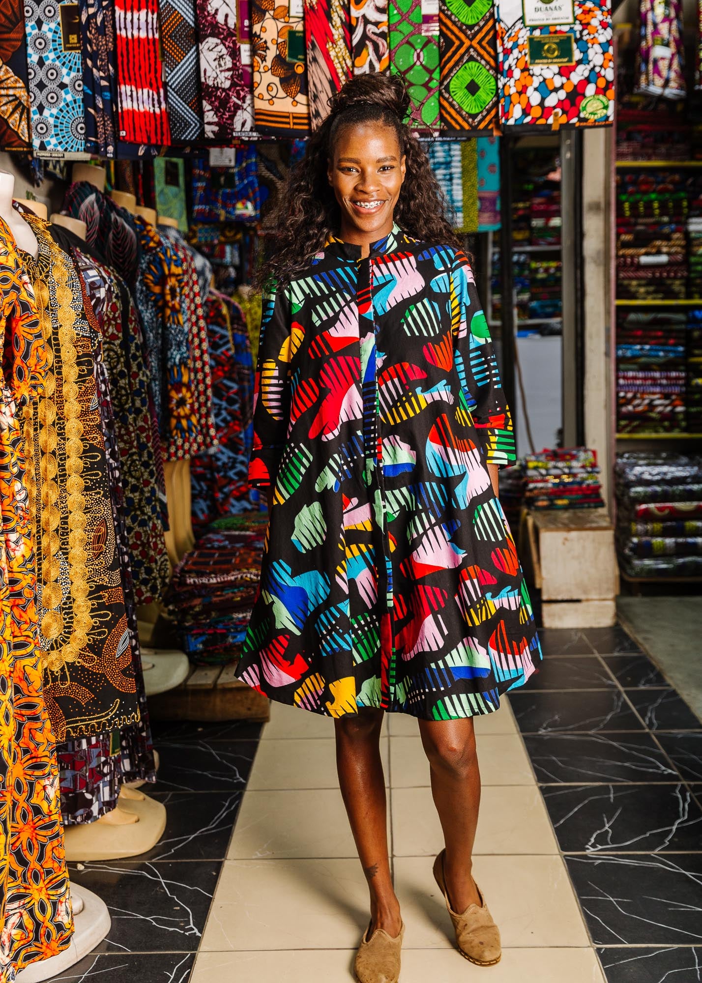 The model is wearing abstract multi-color  figures dress