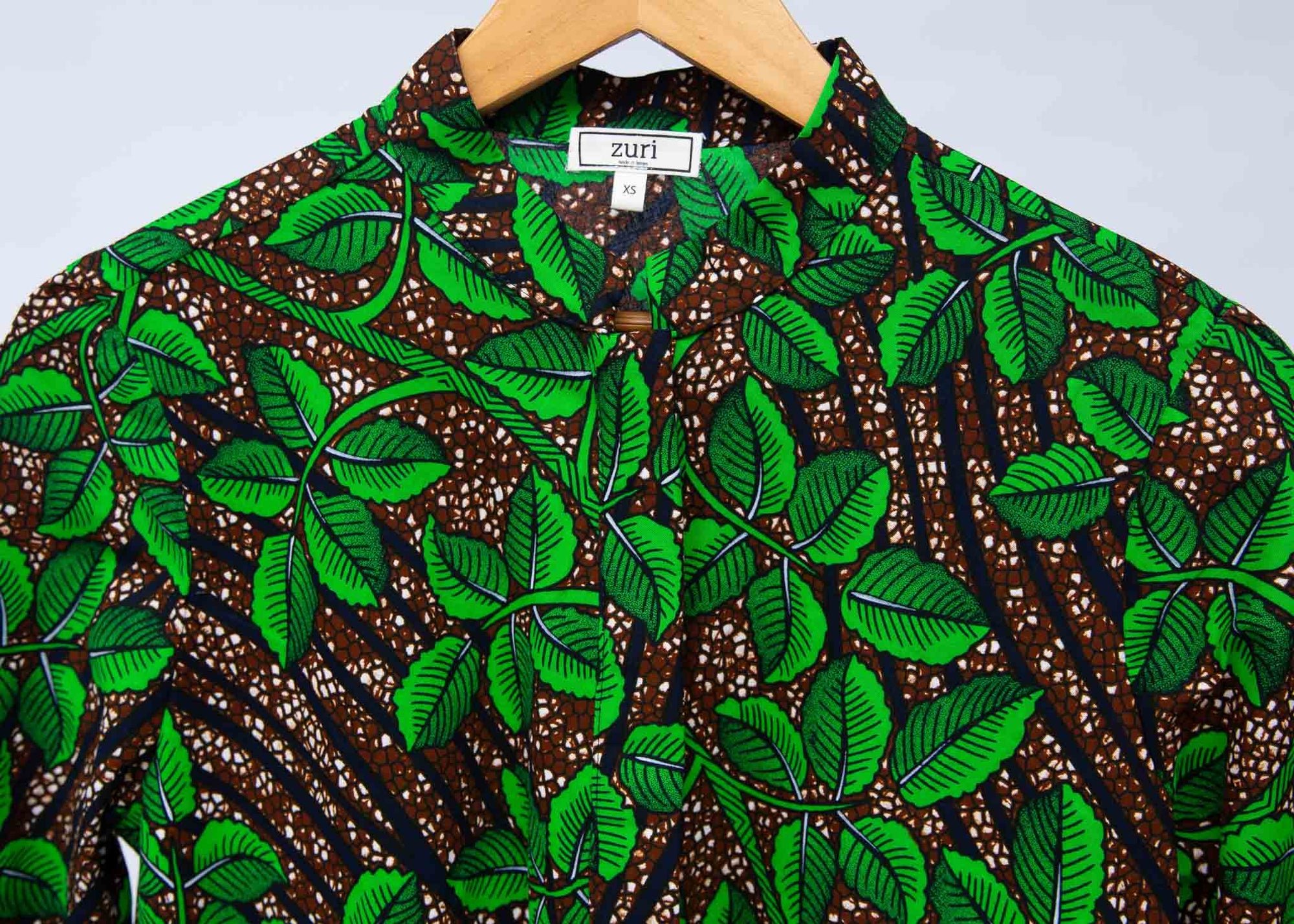 Display of brown dress with green vine print.