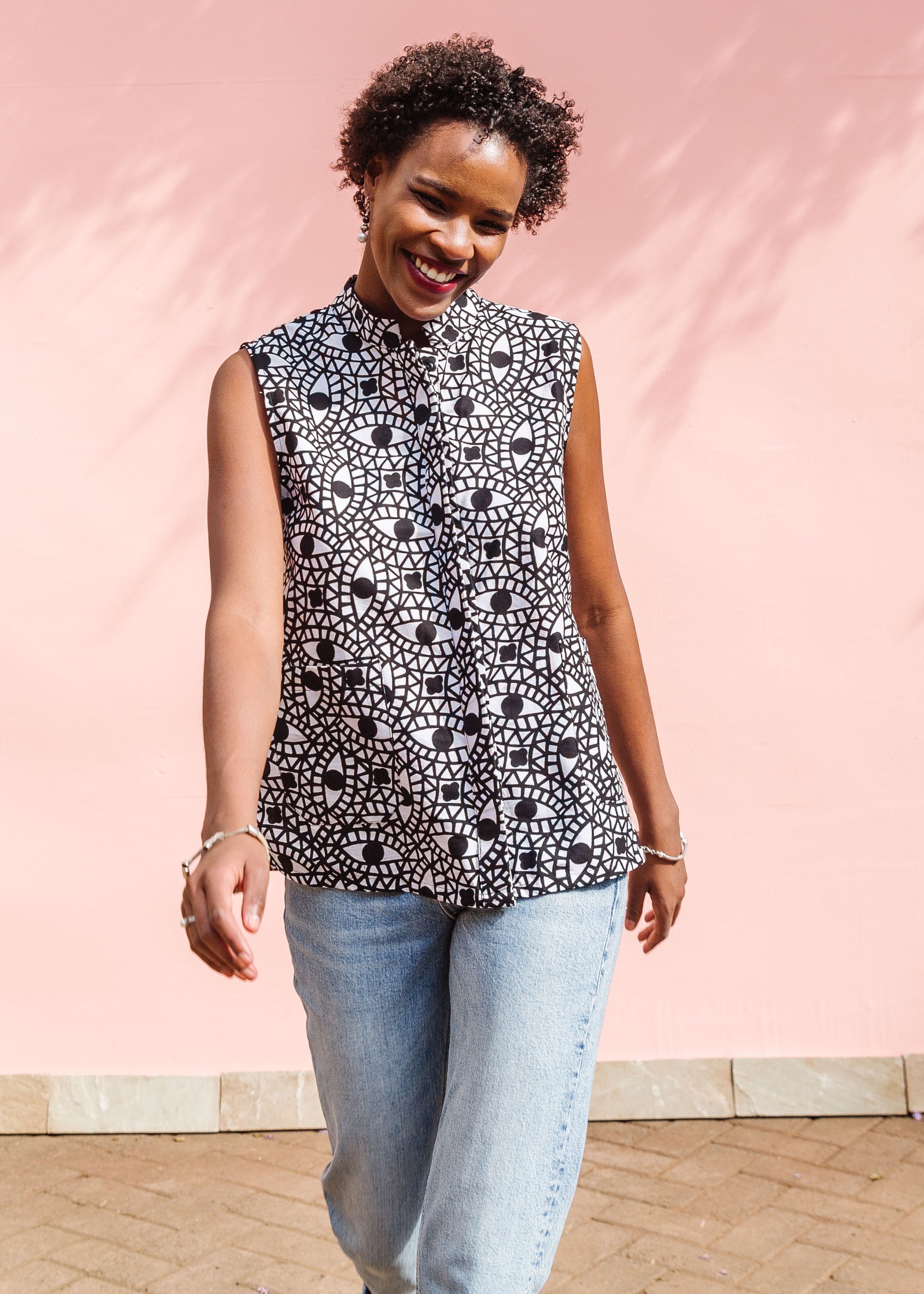 Model wearing black and white eye print sleeveless shirt.