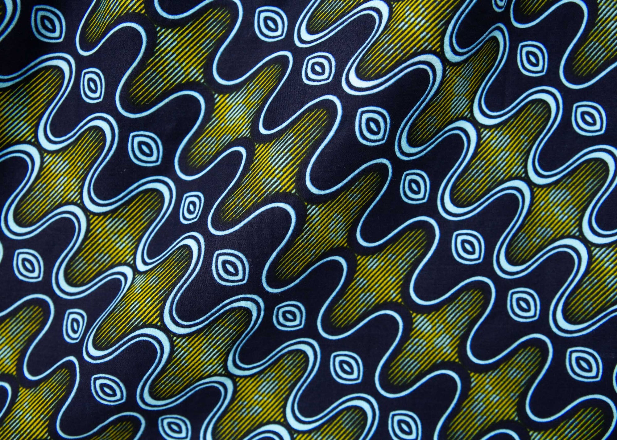 Close up display of long sleeved blue, green and yellow, zig zag print shirt.