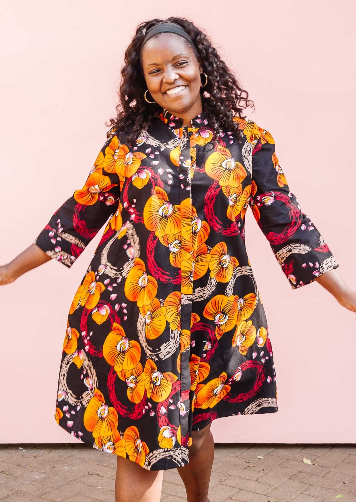 The model is wearing black dress with yellow and pink floral print.