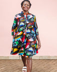 The model is wearing abstract multi-color  figures dress