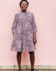 The model is wearing brown and baby pink abstract print dress