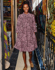 The model is wearing brown and baby pink abstract print dress