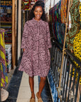 The model is wearing brown and baby pink abstract print dress