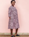 The model is wearing brown and baby pink abstract print dress