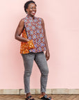 The model is wearing  orange, purple, white and black mixed pattern kanga tank