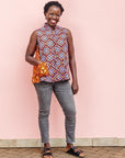 The model is wearing  orange, purple, white and black mixed pattern kanga tank