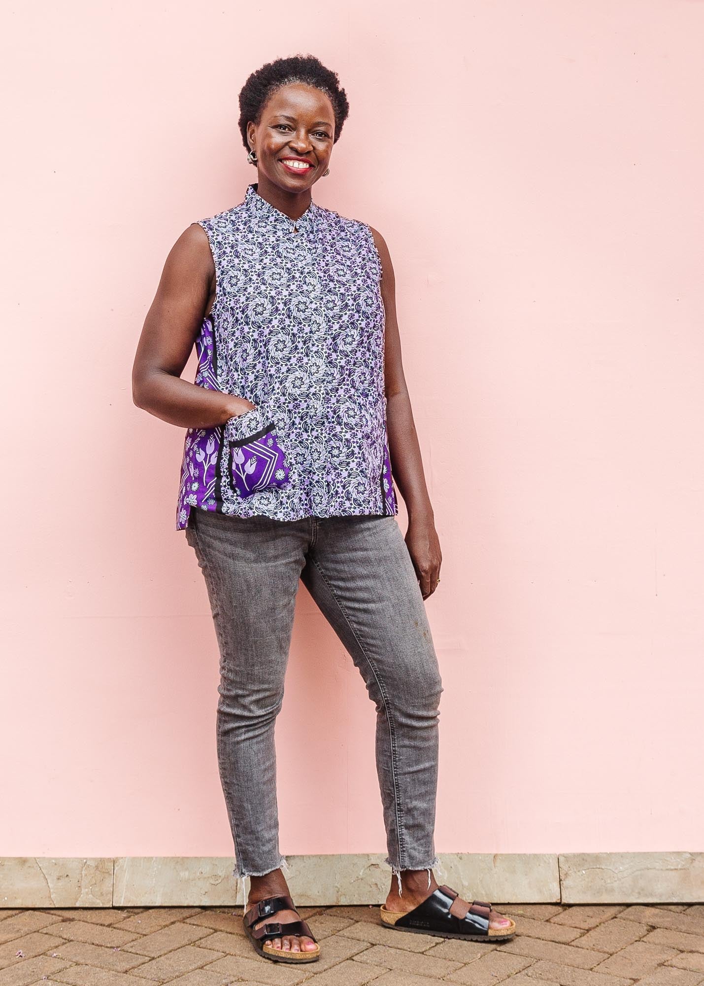 The model is wearing purple, lavender, black and white kanga tank