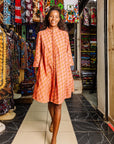 The model is wearing peach-pink, lavender and brown seashell print dress