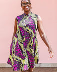 The model is wearing yellow-green dress with purple, black, white fish print 