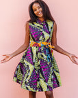 The model is wearing yellow-green dress with purple, black, white fish print 